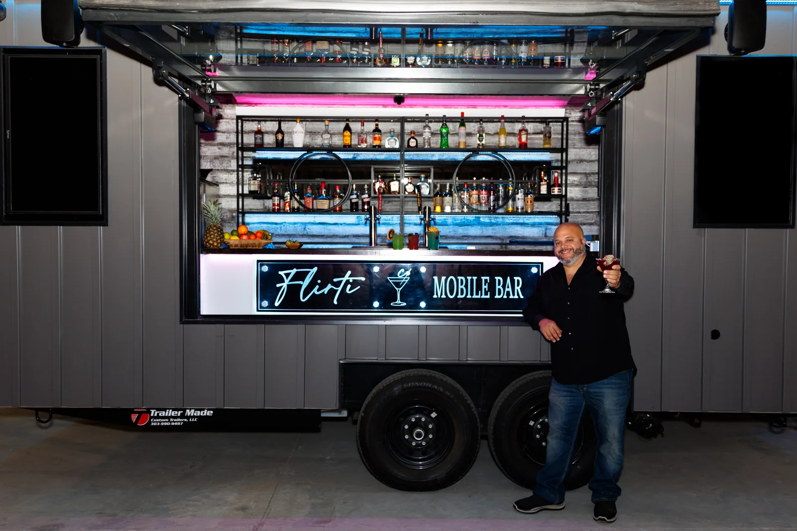 Proprietor toasting beside a completed custom beverage vending trailer